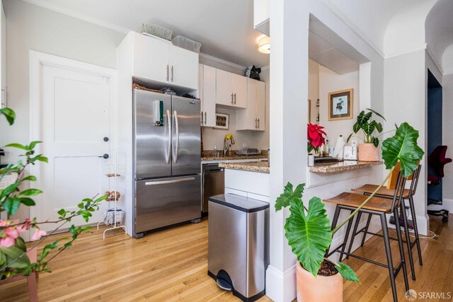 1490 Francisco St Unit 3, San Francisco, CA 94123 - kitchen with freestanding refrigerator, light wood finished floors, white cabinetry, dishwashing machine, and light stone counters