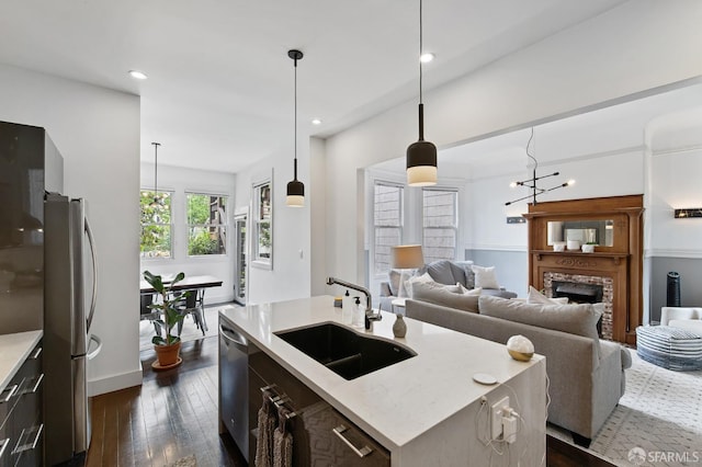 kitchen with appliances with stainless steel finishes, an island with sink, hanging light fixtures, and sink