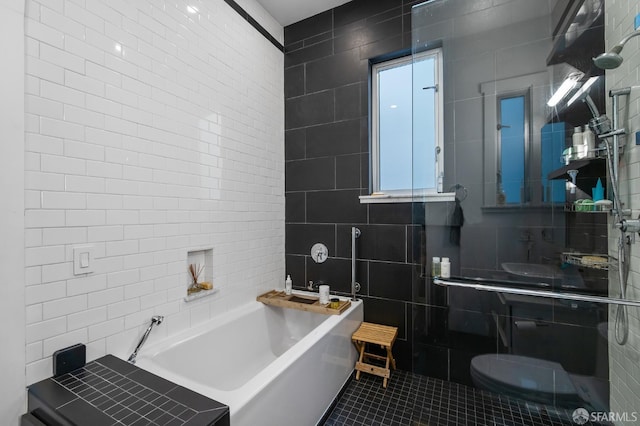 bathroom featuring toilet, tile patterned floors, tile walls, and a bathing tub