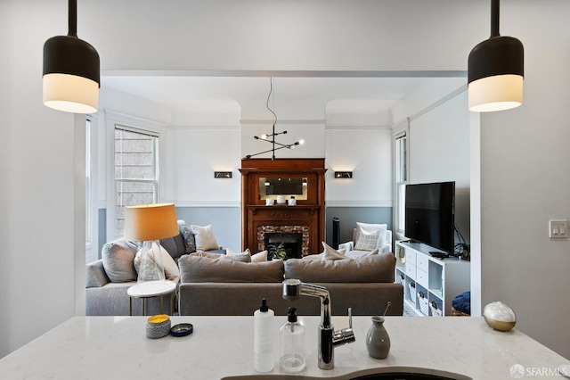 living room featuring a brick fireplace, crown molding, and a chandelier