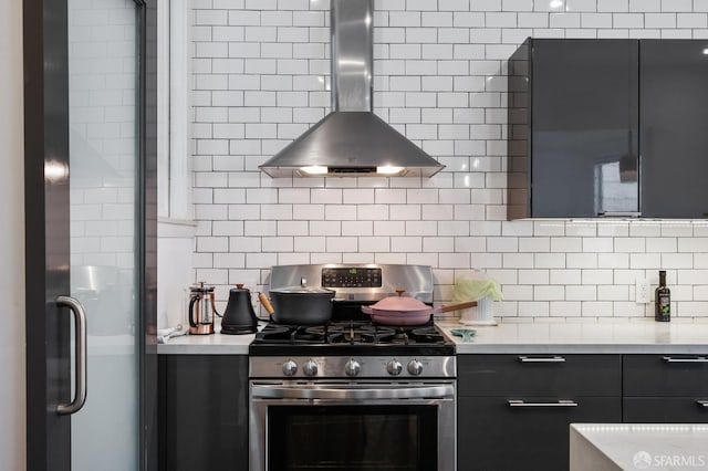 kitchen featuring stainless steel gas range, backsplash, and wall chimney range hood