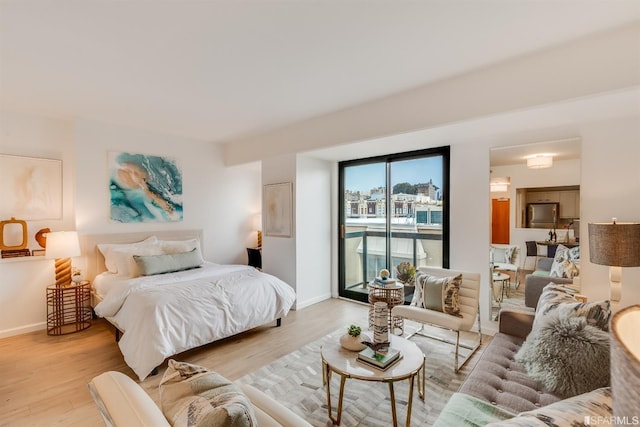 bedroom with stainless steel refrigerator, light hardwood / wood-style floors, and access to exterior