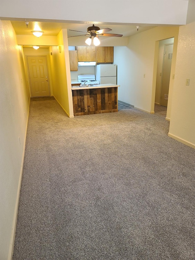 kitchen with a peninsula, white appliances, baseboards, open floor plan, and light countertops