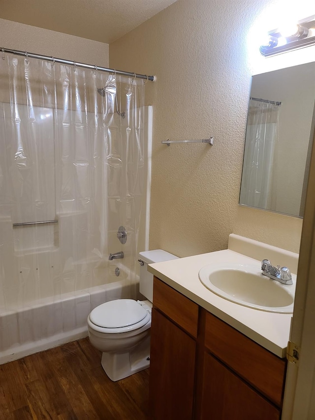 bathroom with shower / bath combination with curtain, a textured wall, toilet, vanity, and wood finished floors