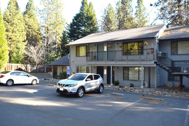 view of front of home featuring stairs, fence, and uncovered parking