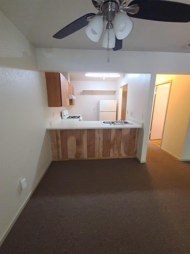 kitchen with range, freestanding refrigerator, a peninsula, light countertops, and carpet flooring