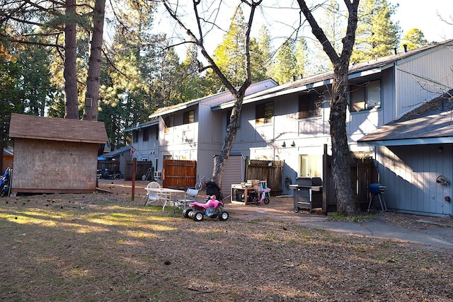 back of property with a storage shed and fence