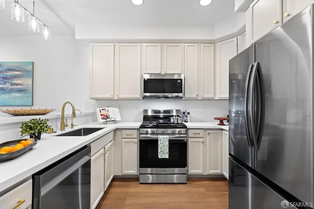 kitchen with a sink, light wood-style floors, appliances with stainless steel finishes, and light countertops