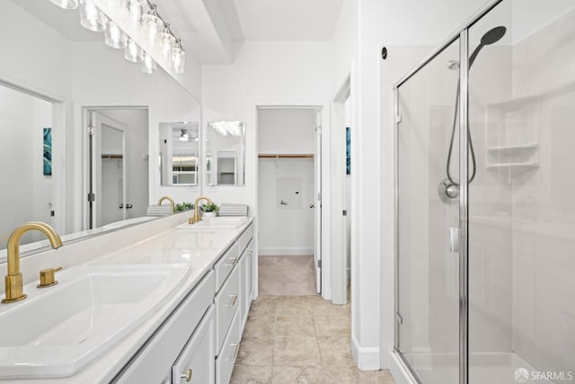 bathroom with double vanity, a spacious closet, a stall shower, and a sink