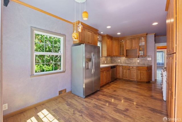 47 Brunswick St, San Francisco, CA 94112 - kitchen featuring brown cabinetry, wood finished floors, light countertops, appliances with stainless steel finishes, and backsplash
