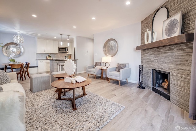 living room with light wood-type flooring and a stone fireplace