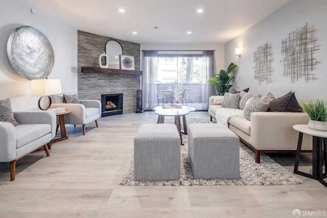 living room featuring light wood-type flooring and a stone fireplace