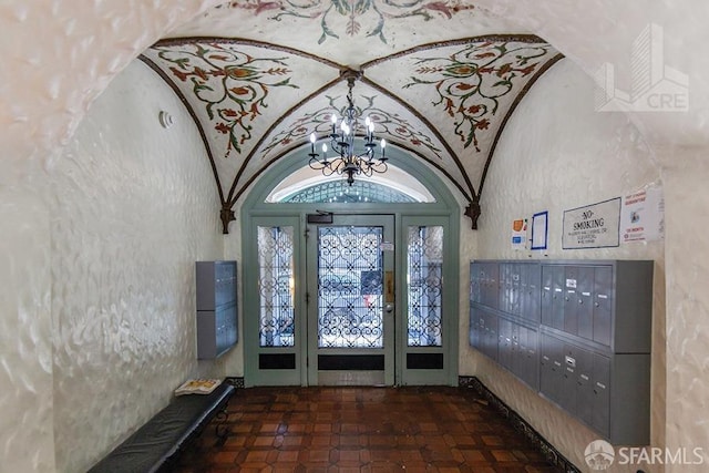 foyer entrance featuring mail area, lofted ceiling, and a notable chandelier