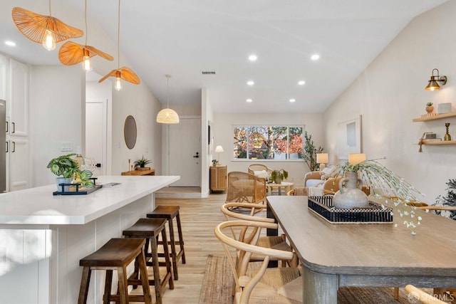 dining area with light hardwood / wood-style floors and vaulted ceiling