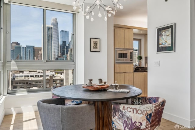 229 Brannan St Unit 11J, San Francisco, CA 94107 - dining room featuring a chandelier, light wood finished floors, a view of skyline, and baseboards