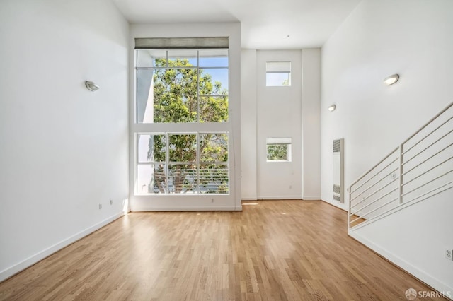 foyer entrance with a healthy amount of sunlight, a towering ceiling, and light hardwood / wood-style flooring