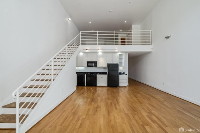 interior space with light hardwood / wood-style floors and a towering ceiling