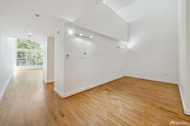 spare room with electric panel and light wood-type flooring