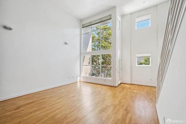 spare room with light wood-type flooring and a towering ceiling