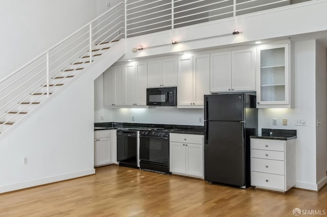 kitchen with light hardwood / wood-style flooring, black appliances, and white cabinetry