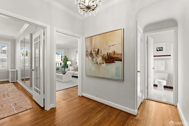 hall with hardwood / wood-style flooring, crown molding, and an inviting chandelier