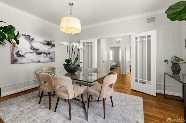 dining space featuring hardwood / wood-style flooring, crown molding, and french doors