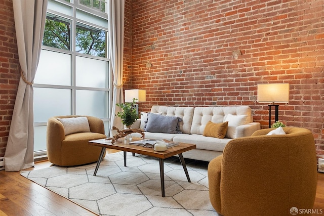 living area with hardwood / wood-style flooring and brick wall