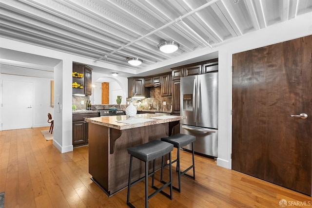 kitchen with a breakfast bar, dark brown cabinets, light wood-style floors, and appliances with stainless steel finishes