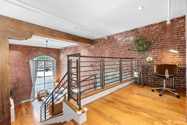 office space with hardwood / wood-style floors, beam ceiling, and brick wall