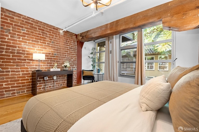 bedroom with wood finished floors and brick wall