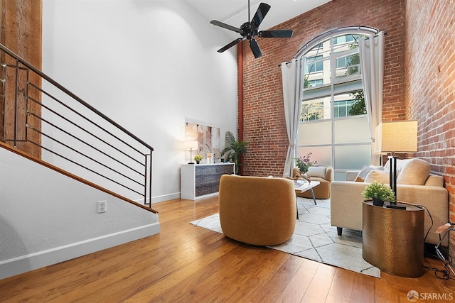 interior space featuring hardwood / wood-style floors, stairway, a high ceiling, brick wall, and ceiling fan