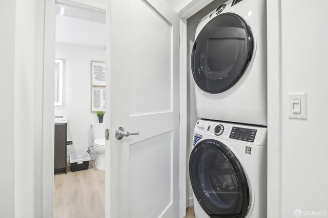 clothes washing area featuring light hardwood / wood-style floors and stacked washer / drying machine