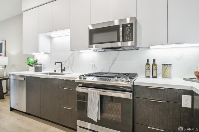 kitchen with sink, white cabinets, stainless steel appliances, and dark brown cabinets