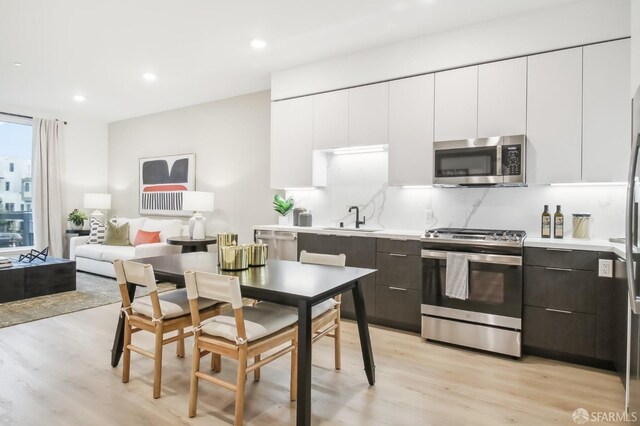 kitchen featuring white cabinets, sink, light hardwood / wood-style floors, dark brown cabinetry, and stainless steel appliances