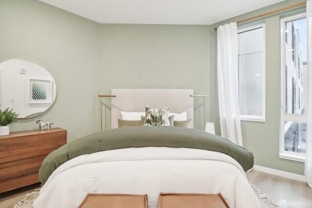 bedroom with light hardwood / wood-style floors and multiple windows