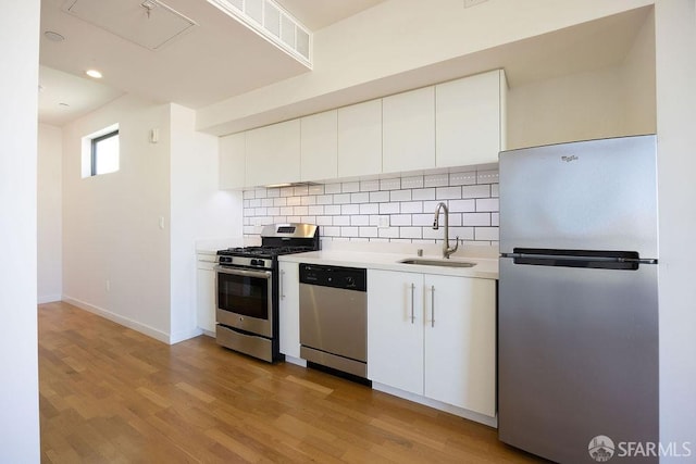 kitchen featuring appliances with stainless steel finishes, light wood-type flooring, white cabinetry, and sink