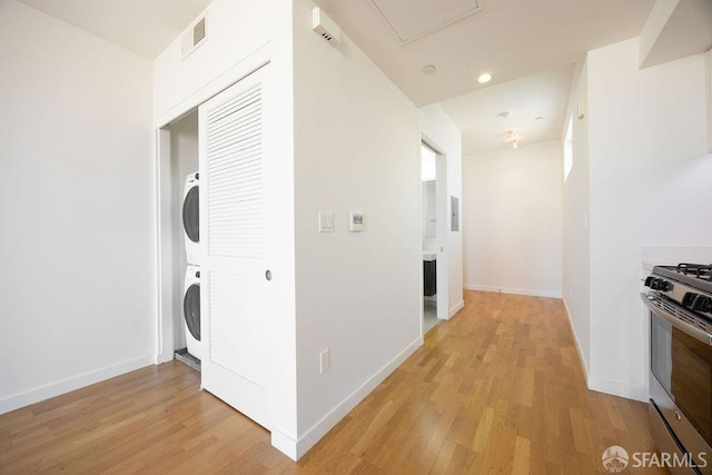 washroom with stacked washer / drying machine and light wood-type flooring