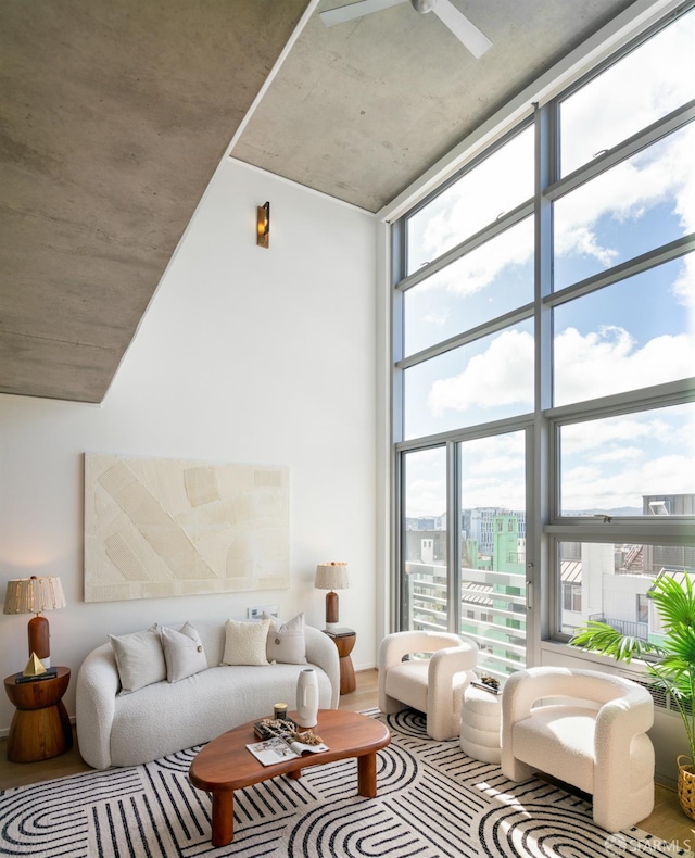 living room featuring a towering ceiling, wood finished floors, ceiling fan, and floor to ceiling windows