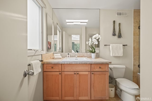 full bath featuring visible vents, toilet, tasteful backsplash, a tile shower, and vanity