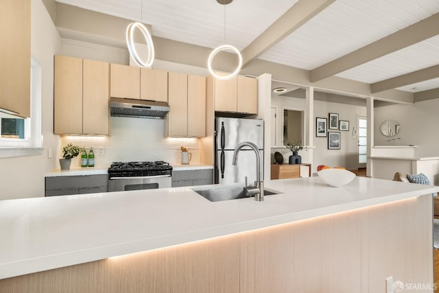 kitchen with backsplash, under cabinet range hood, beamed ceiling, appliances with stainless steel finishes, and a sink