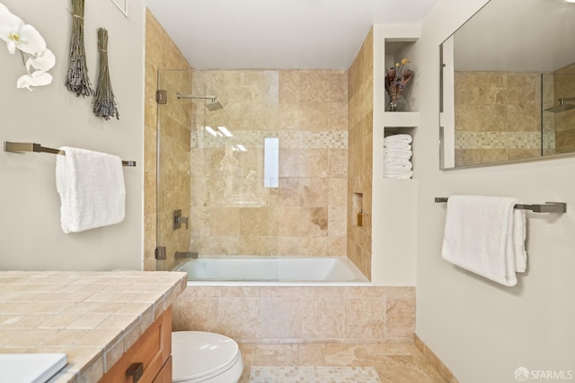 bathroom featuring vanity, toilet, and tiled shower / bath