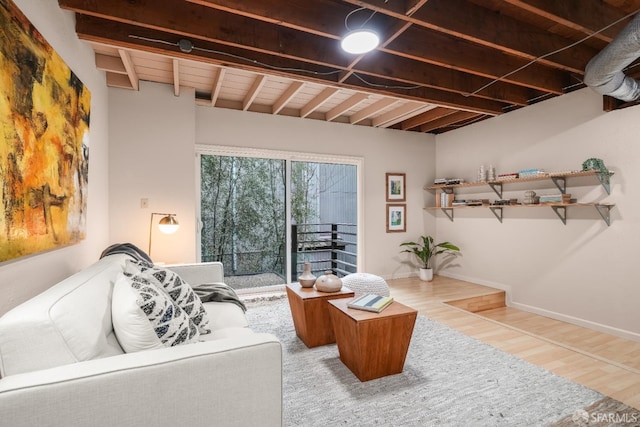 living area featuring beamed ceiling, baseboards, and wood finished floors