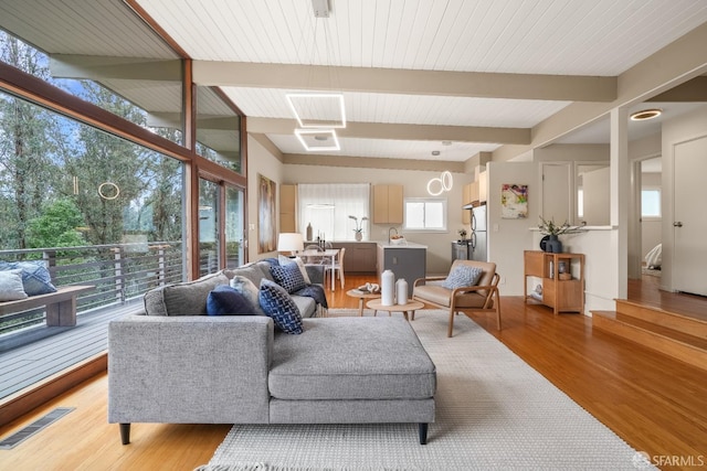 living area with visible vents, beamed ceiling, light wood-style flooring, and floor to ceiling windows