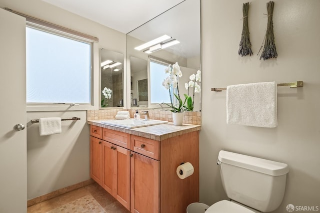 bathroom with plenty of natural light, tasteful backsplash, vanity, and toilet