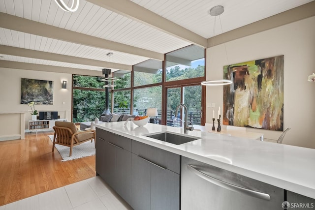 kitchen featuring a sink, light countertops, stainless steel dishwasher, beamed ceiling, and open floor plan