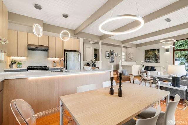 dining space featuring light wood-type flooring and beamed ceiling