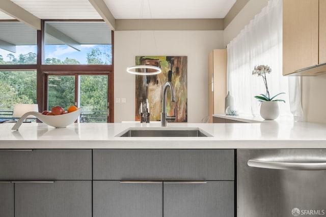 kitchen with stainless steel dishwasher, light countertops, gray cabinets, and a sink