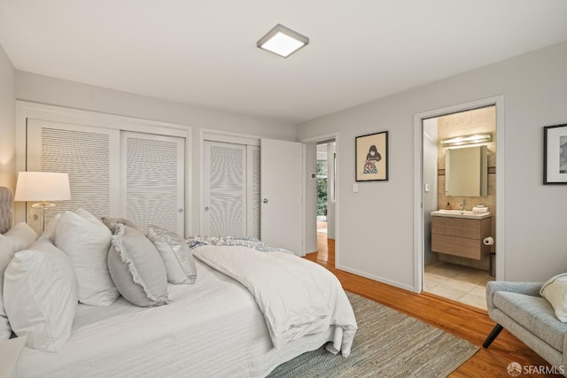 bedroom featuring light wood-style flooring, ensuite bathroom, and baseboards