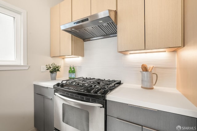 kitchen with tasteful backsplash, extractor fan, light countertops, gray cabinets, and stainless steel gas range