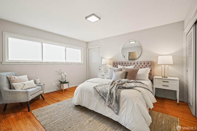 bedroom with wood finished floors, a closet, and baseboards